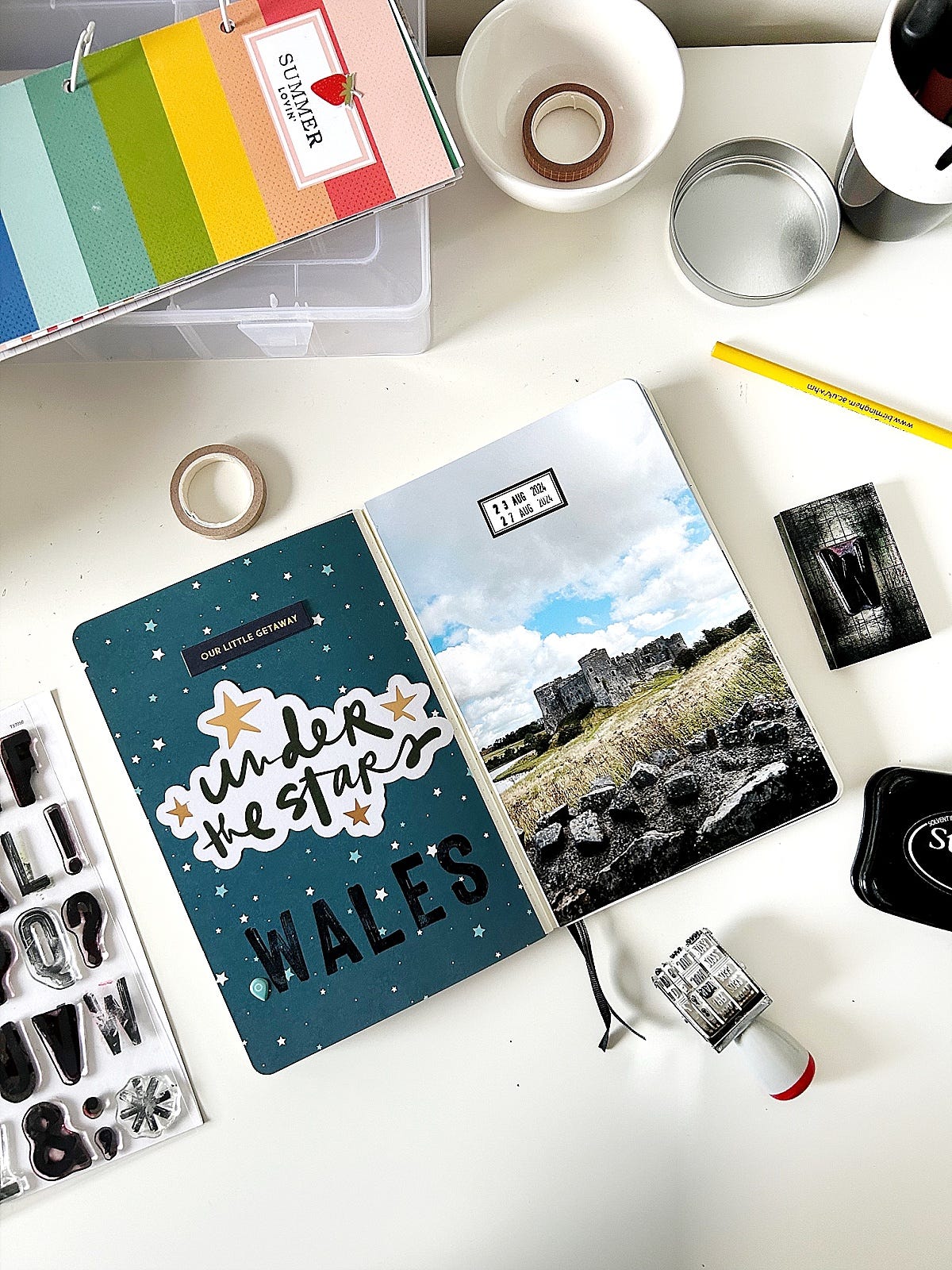 travel journal lying open on desk with craft supplies