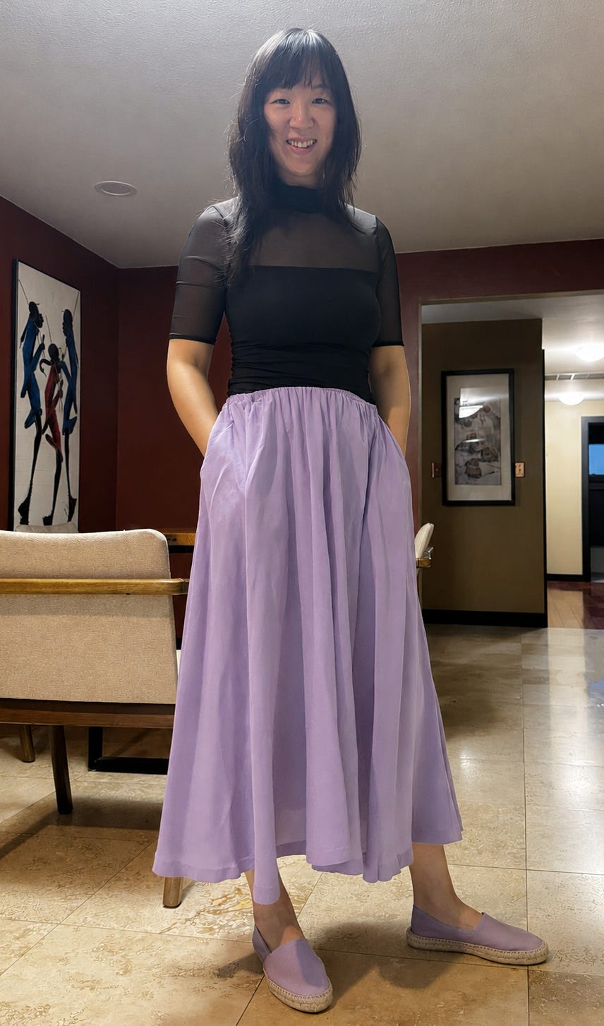 a woman stands with one hand tucked into the pocket of a flowing lilac skirt a woman stands with one hand tucked into the pocket of a flowing lilac skirt