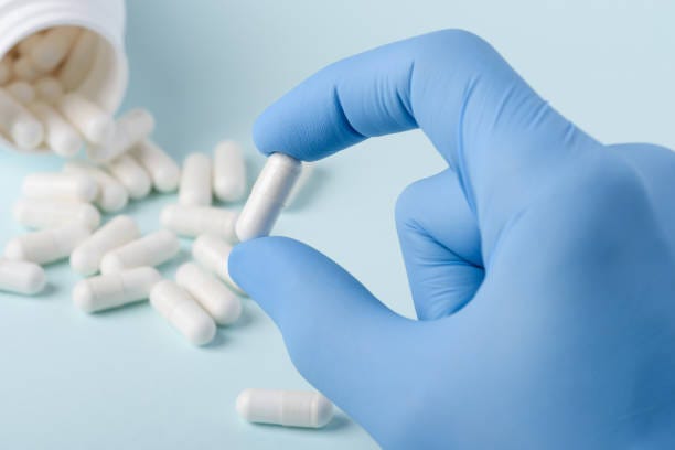 Single pill with white substance in scientist hand Single pill with white substance in scientist hand, bottle on background pharma stock pictures, royalty-free photos & images