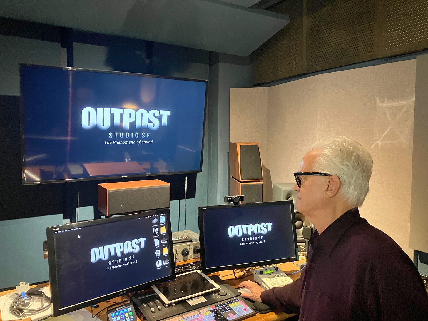 David works at a sound mixing station inside Outpost Studios, surrounded by monitors and audio equipment.