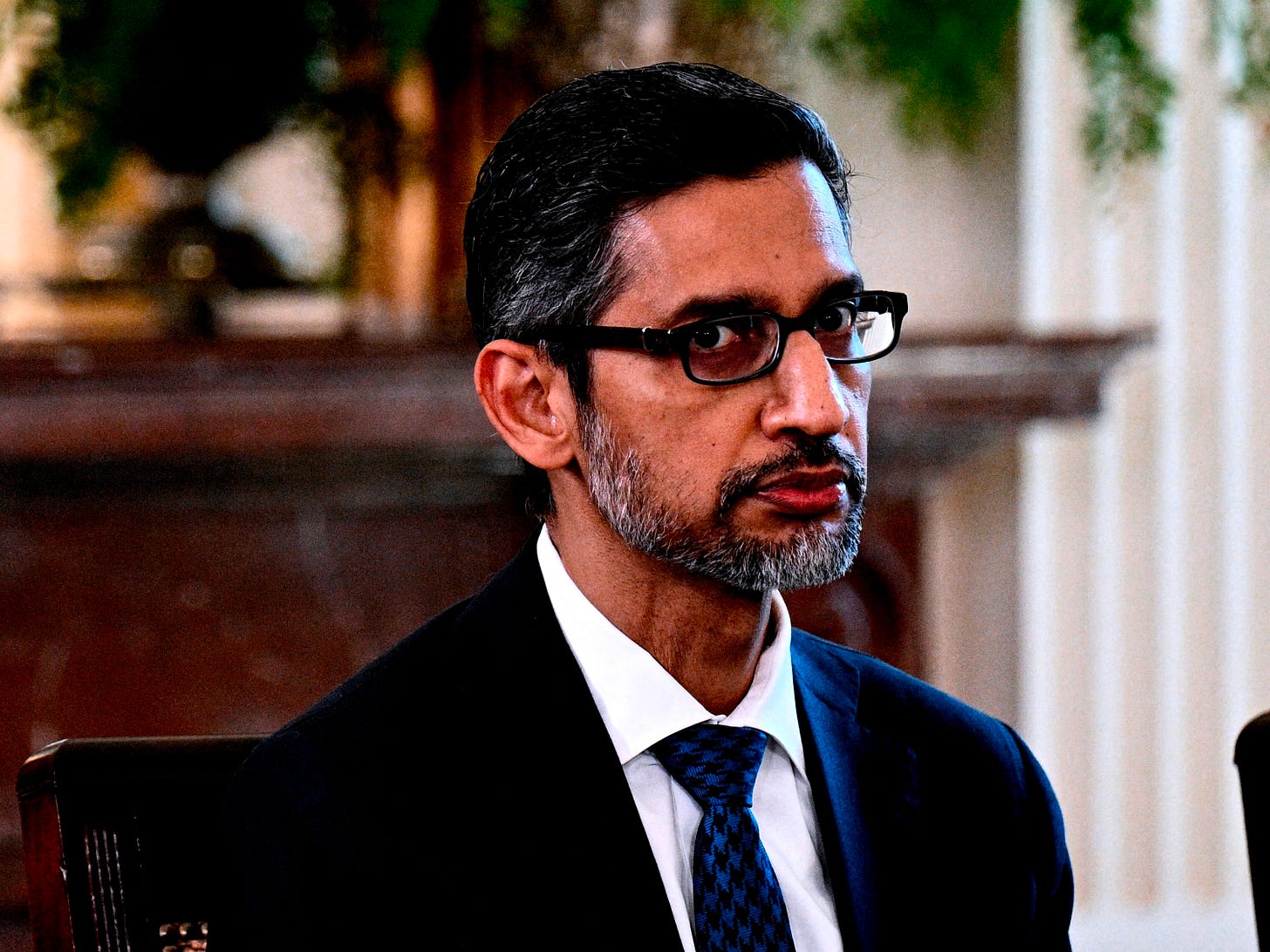 Google CEO Sundar Pichai looking out solemnly while wearing a suit.