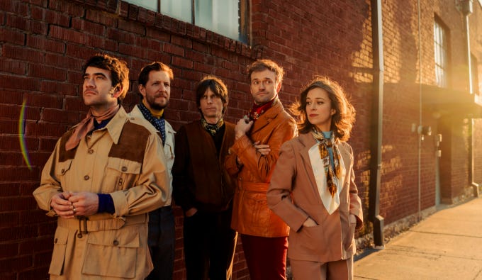 punch brothers standing in front of a brick building during sunset. punch brothers standing in front of a brick building during sunset.
