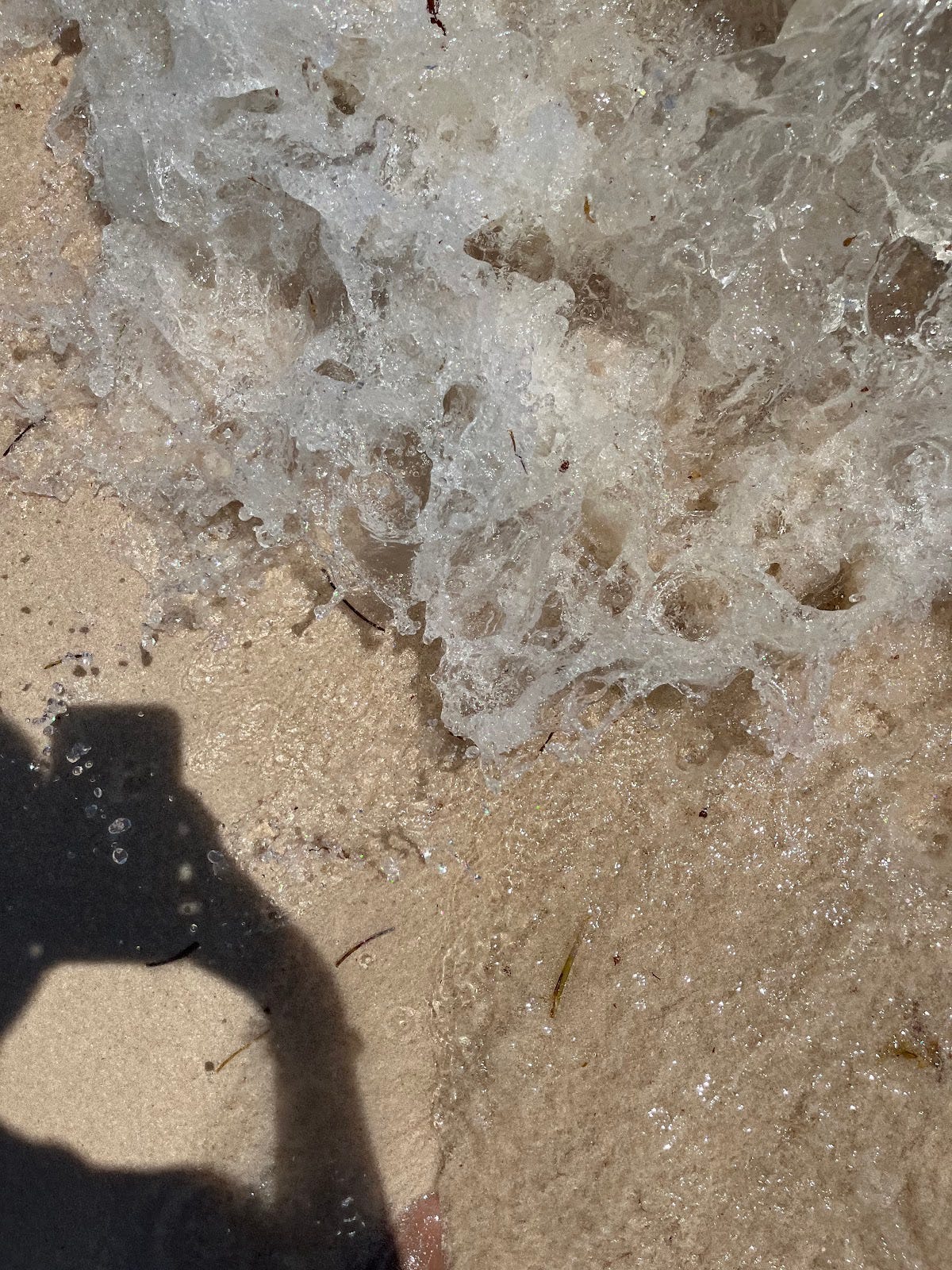 A still of a wave crashing into the shore from overhead, but from a person's height