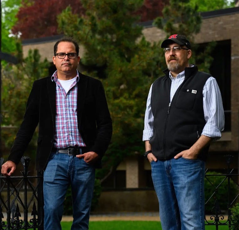 Two men standing outside in front of a fence

AI-generated content may be incorrect.