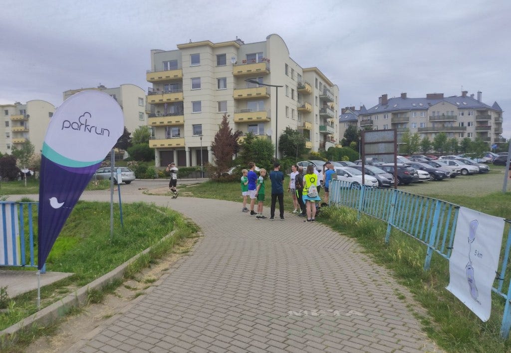 People gathered on the paved path at the finish, with apartment blocks behind.