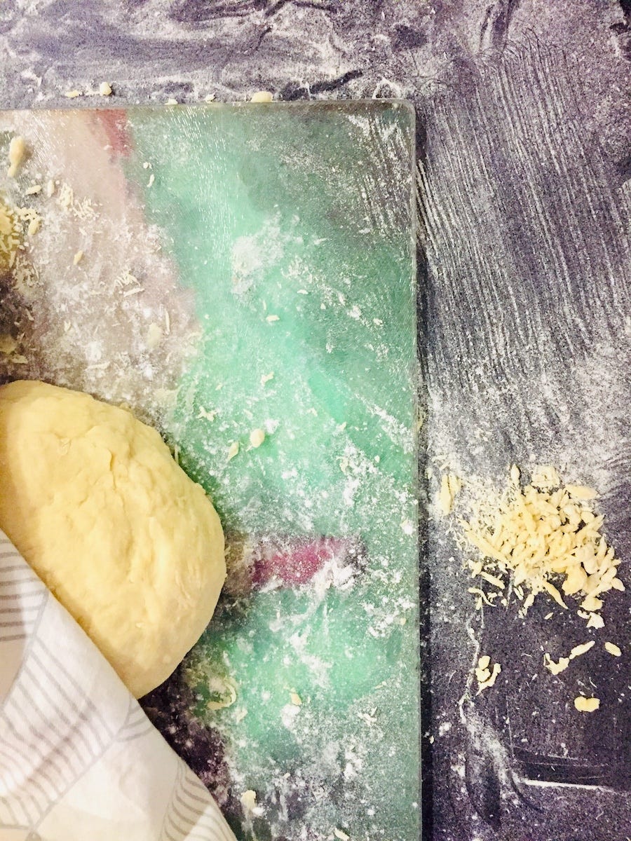 photo of a messy kitchen counter top with flour all over, half a dough peeking out under a cloth towel