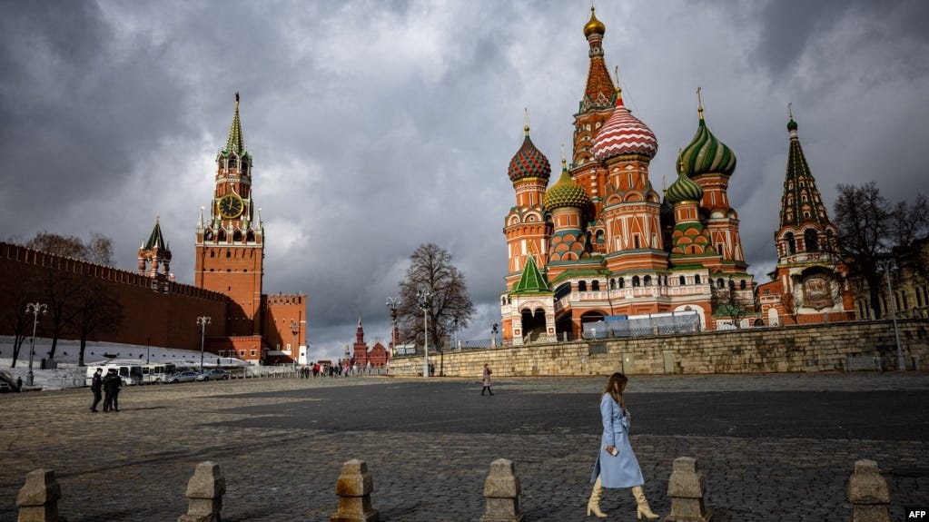 FILE - A woman walks under cloudy skies near the Kremlin and St. Basil's Cathedral in central Moscow, Russia, Feb. 22, 2022. FILE - A woman walks under cloudy skies near the Kremlin and St. Basil's Cathedral in central Moscow, Russia, Feb. 22, 2022.