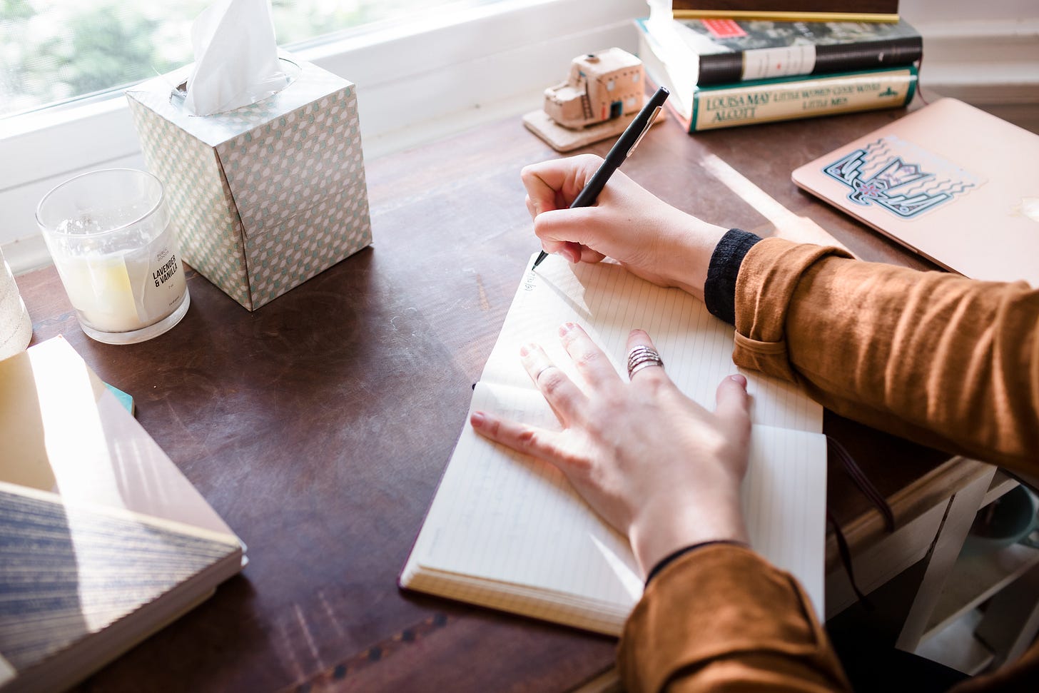 Kaitlin's hands are stretched over a journal, about to write something at her desk 