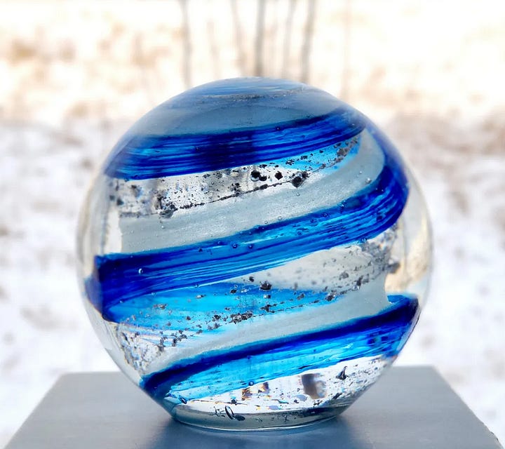 Glass orb containing cremains and blue ribbons