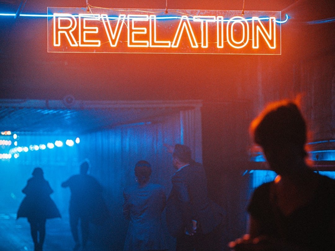 a group of people standing under a neon sign
