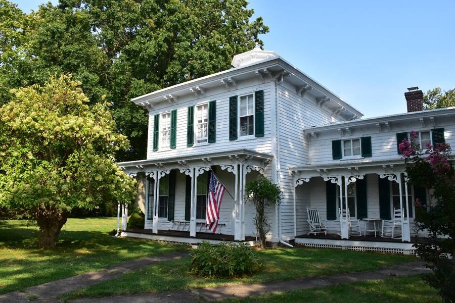 A white house with a flag on the porch

Description automatically generated with low confidence