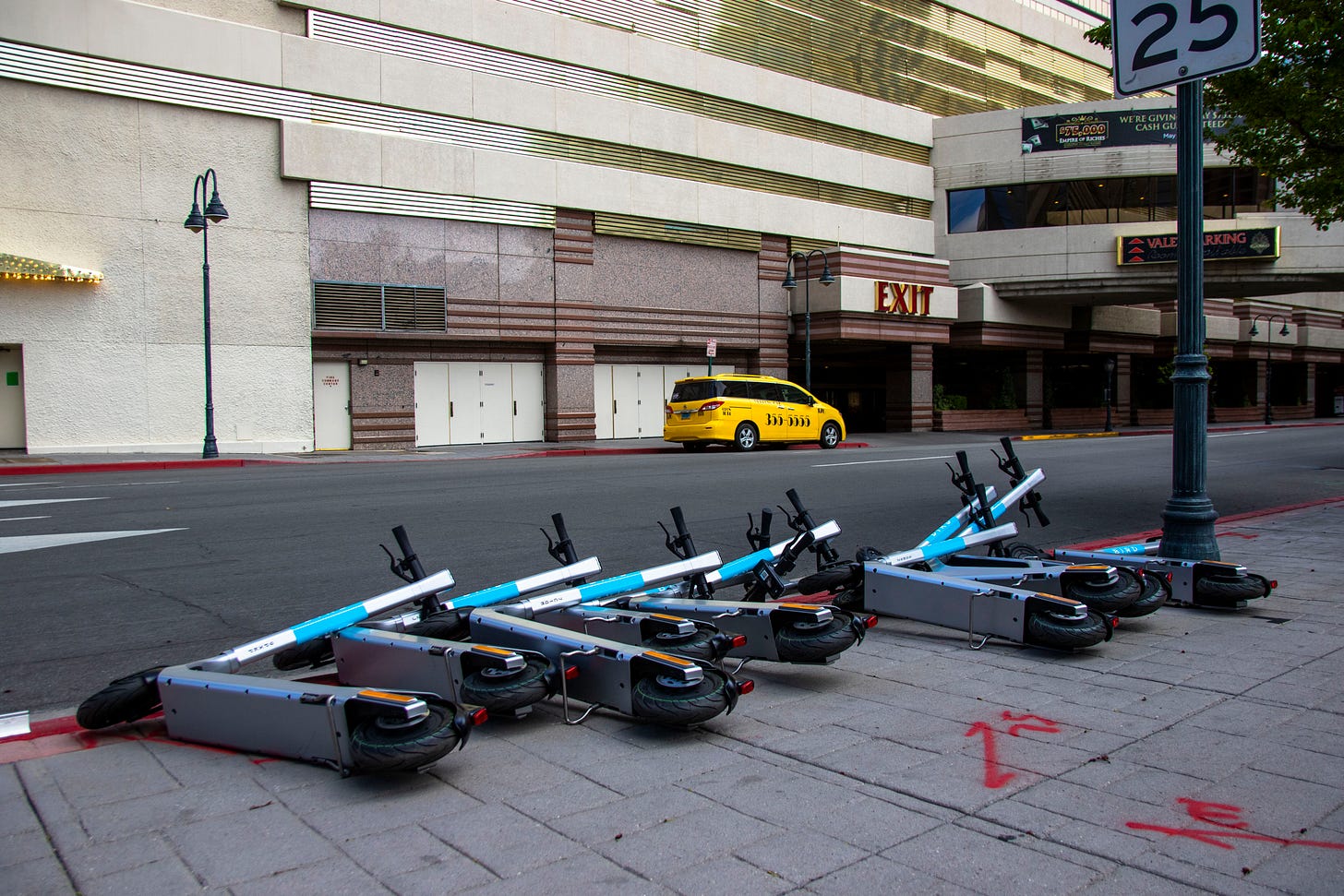 Bird scooters lie on their sides on a sidewalk.