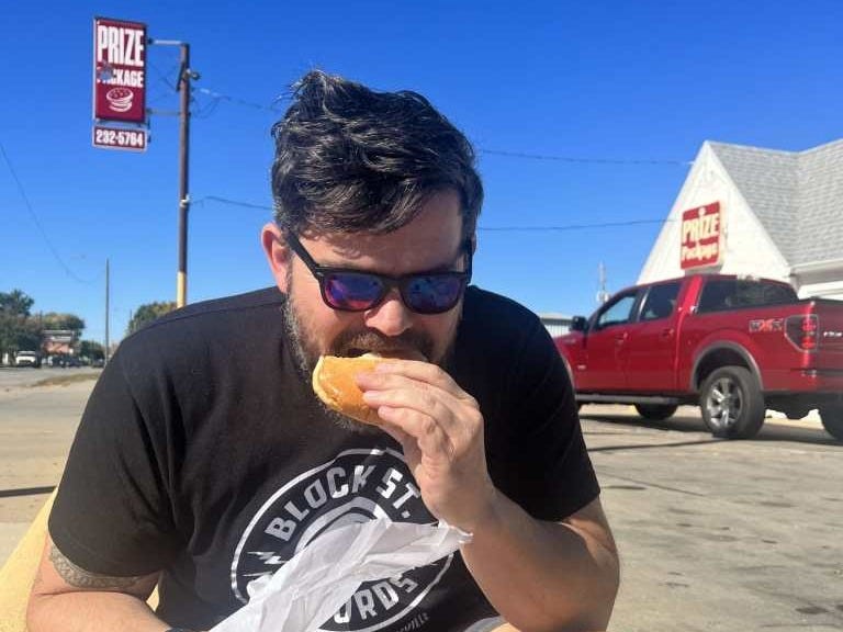 Steven Kimmi eating a burger outside of Prize Package in Topeka, KS