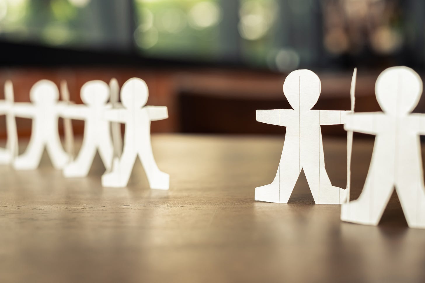 disconnected human paper chain with two sides reaching for each other