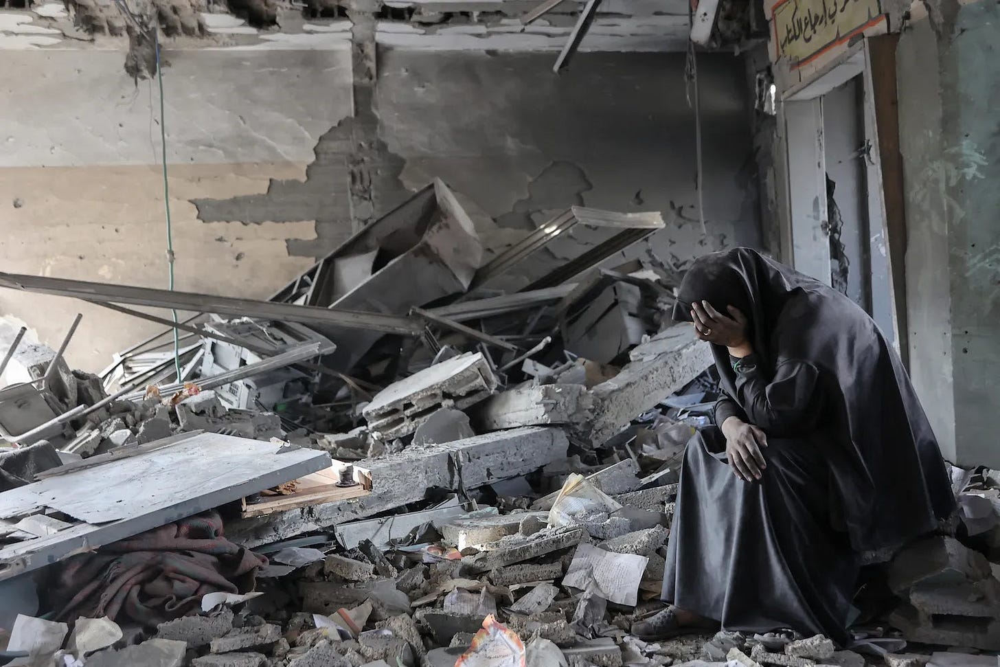 A Palestinian woman sits amid the rubble of a Gaza City school hit by overnight Israeli strikes.