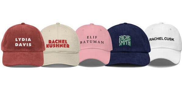 A row of baseball hats embroidered with the names of female authors, from left to right: Lydia Davis, Rachel Kushner, Elif Batuman, Zadie Smith, Rachel Cusk.