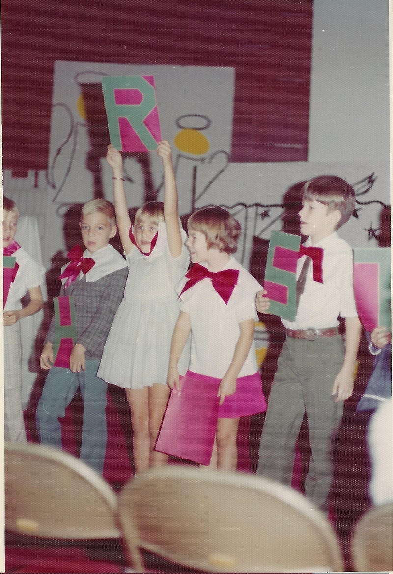 Little kid holding up an R