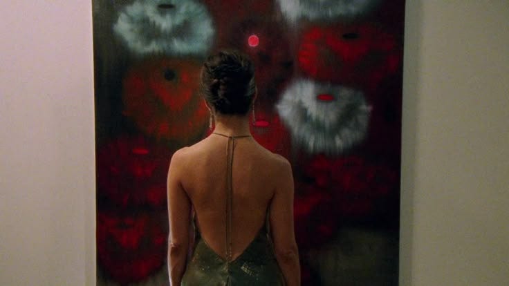 This may contain: a woman standing in front of a painting on the wall with her back to the camera