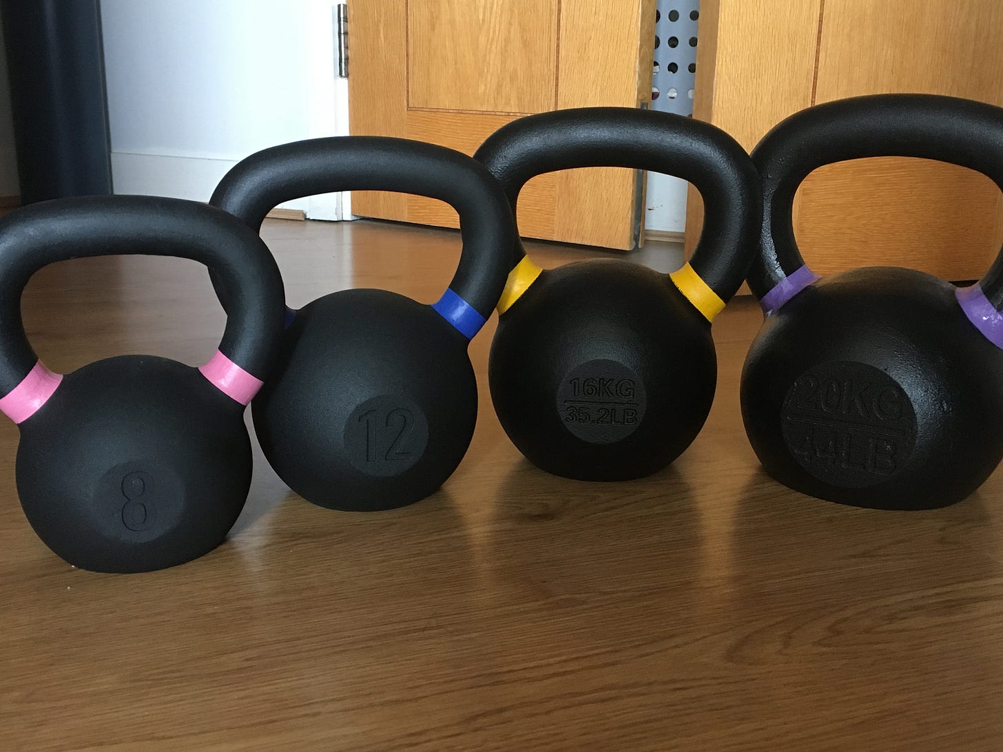 4 cast iron kettlebells in a row, 8kg, 12kg, 16kg, 20kg