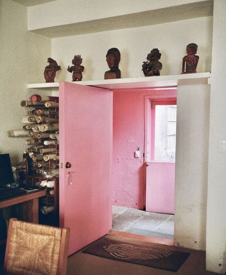 This may contain: a pink door in a room with statues on the wall