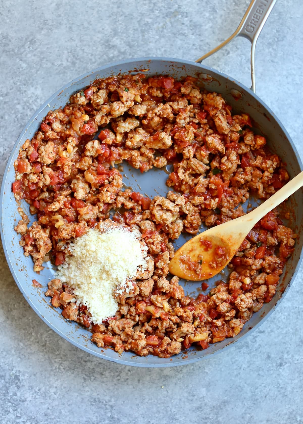 a skillet of ground turkey in it and a wooden spoon.