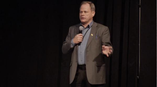 Man in a suit on a state with a microphone