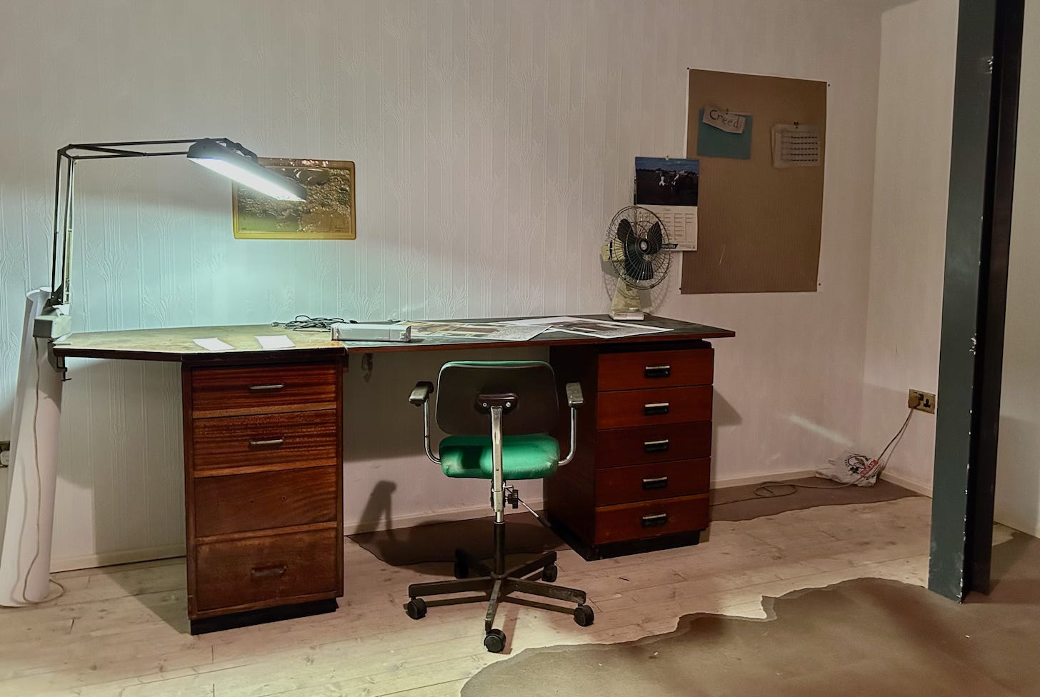 Mike Nelson artist and sculpture reproduced this office space of desk chair and table lamp from his visit to an abandoned housing estate in south London. This was exhibited at Fruitmarket in Edinburgh in the summer of 2025.