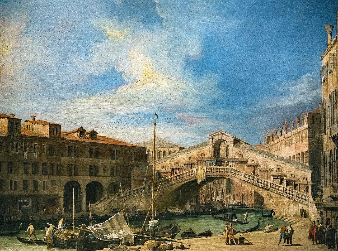 The stone Rialto Bridge arches over a busy Grand Canal full of gondolas under a clear sky The stone Rialto Bridge arches over a busy Grand Canal full of gondolas under a clear sky