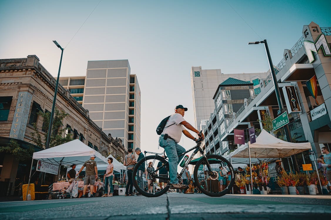 Free Cyclist navigating a bustling outdoor market in a vibrant urban city setting. Stock Photo