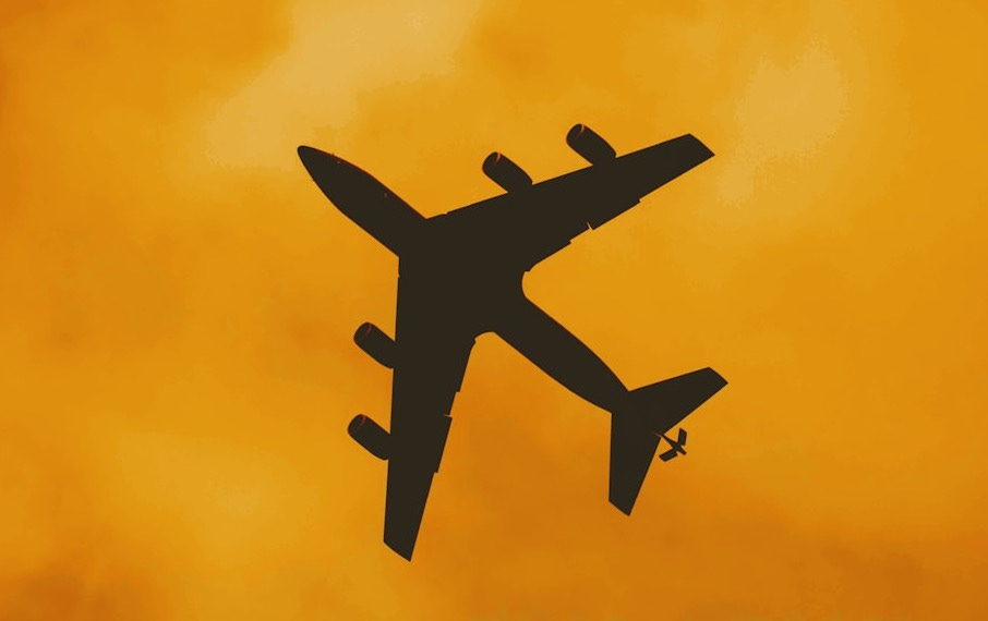 silhouette of airplane under orange cloudy sky silhouette of airplane under orange cloudy sky