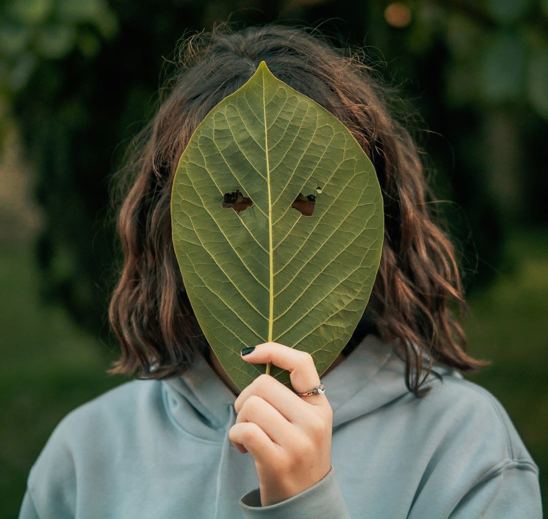 woman in gray long sleeve shirt holding green leaf