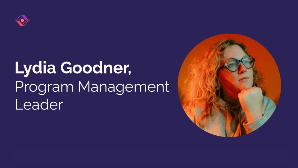 Lydia Goodner, Program Management Leader. Portrait of a woman with curly red hair and round glasses against an orange background, on a dark purple card with the Sendfull logo. Lydia Goodner, Program Management Leader. Portrait of a woman with curly red hair and round glasses against an orange background, on a dark purple card with the Sendfull logo.