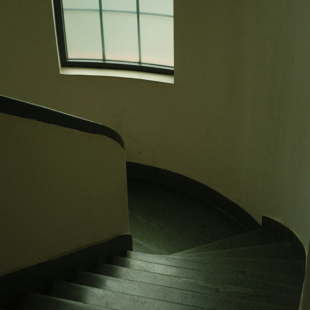 a spiral staircase leading to a window in a building