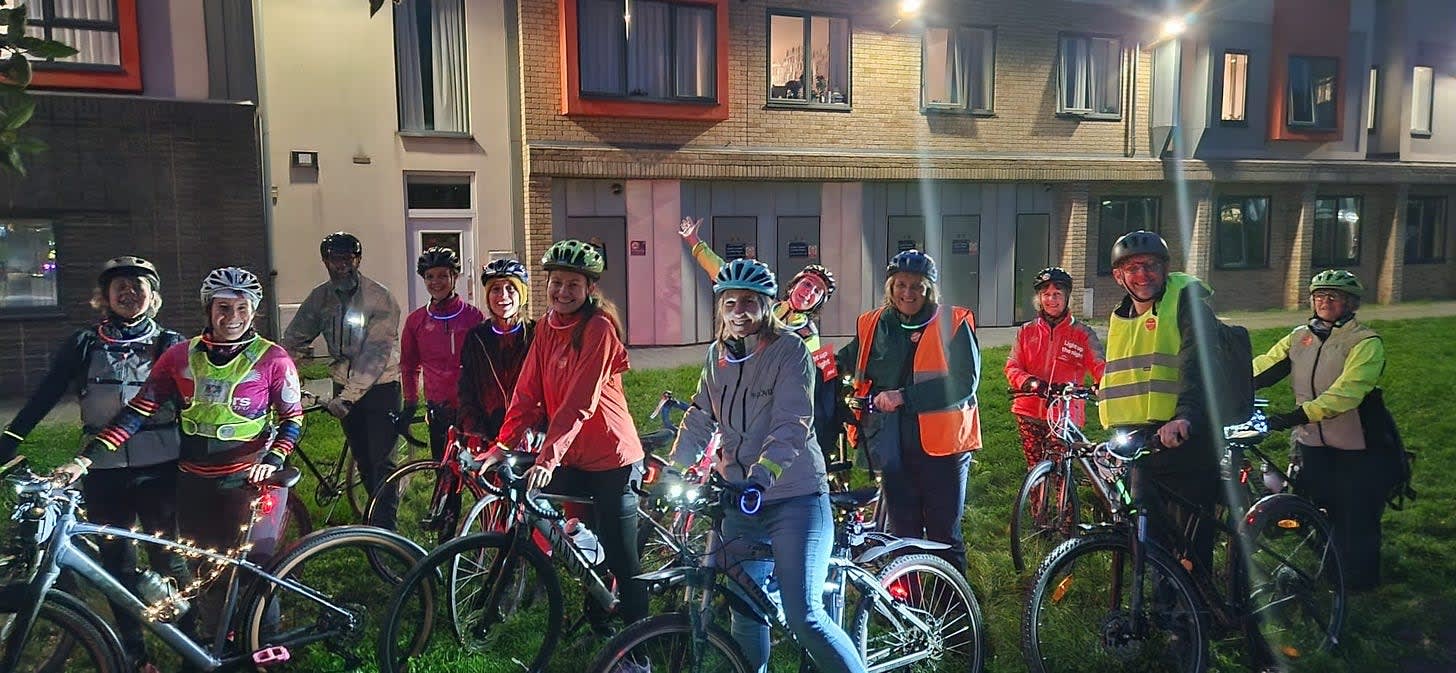 A group of cyclists standing with adorned with glowing lights. A group of cyclists standing with adorned with glowing lights.