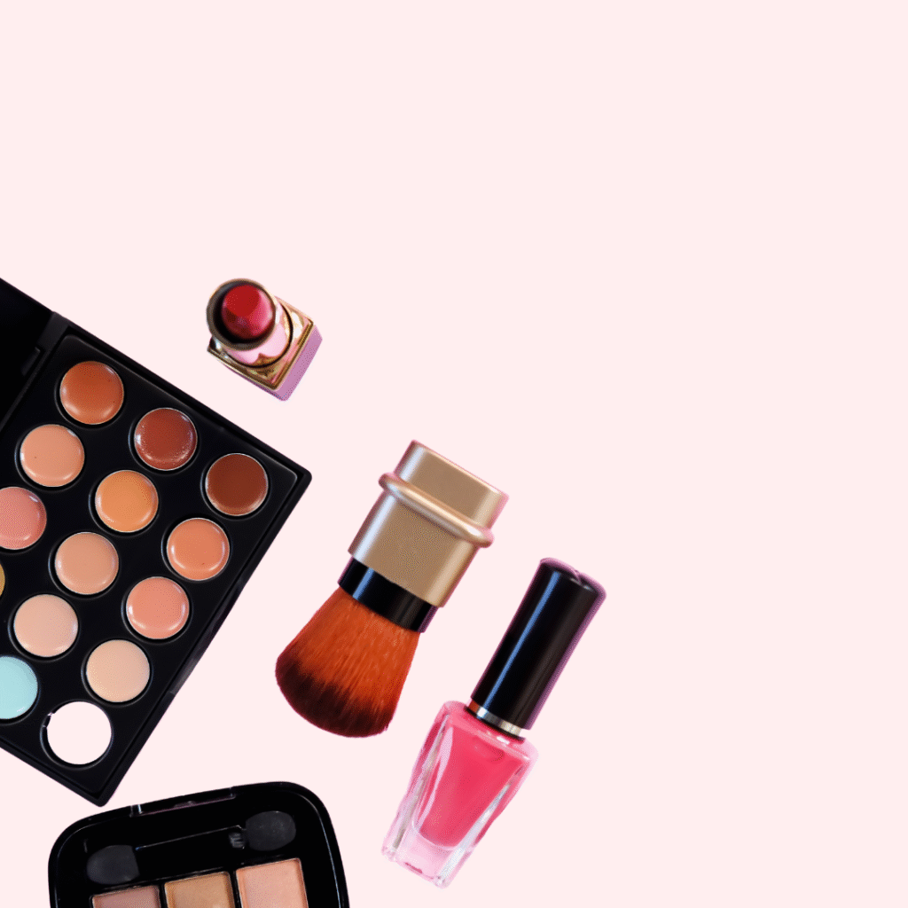 A photo of makeup items. There is a multi-coloured make up palate, red lipstick, blush brush, eye makeup and pin nail polish coming from the bottom left side of the photo.