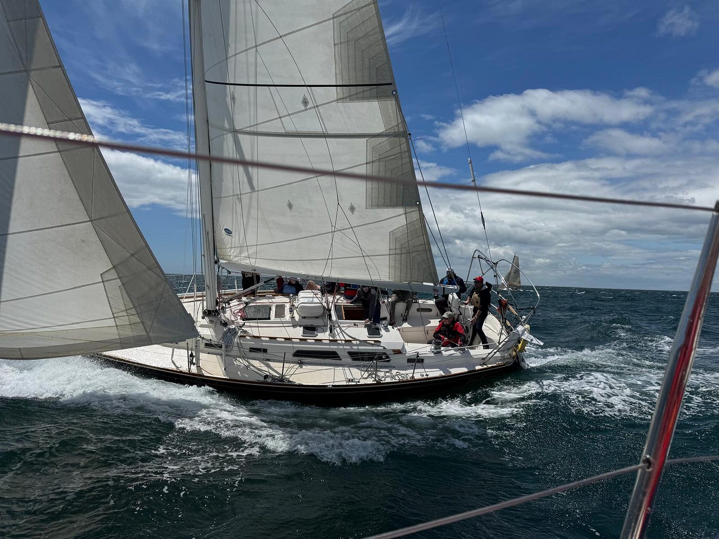 Sailboat under full sail on the crest of a wave.