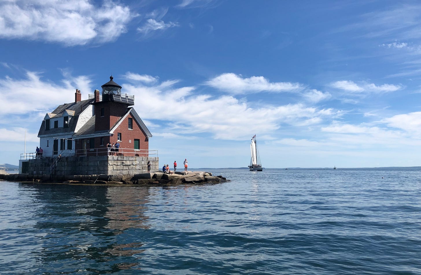 Lighthouse in harbor with sailboat