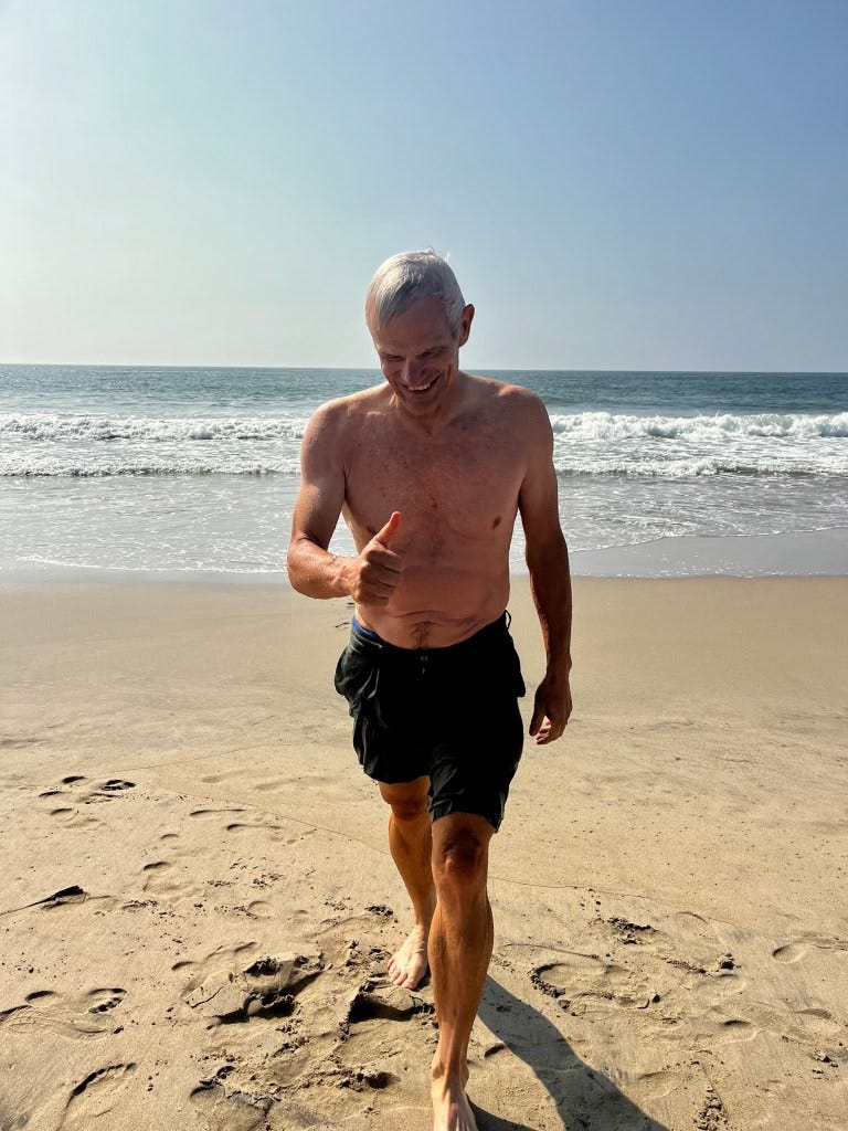 A wet and beaming Markus Suter gives a thumbs up after a swim in the refreshing ocean on Santa Monica State Beach.
