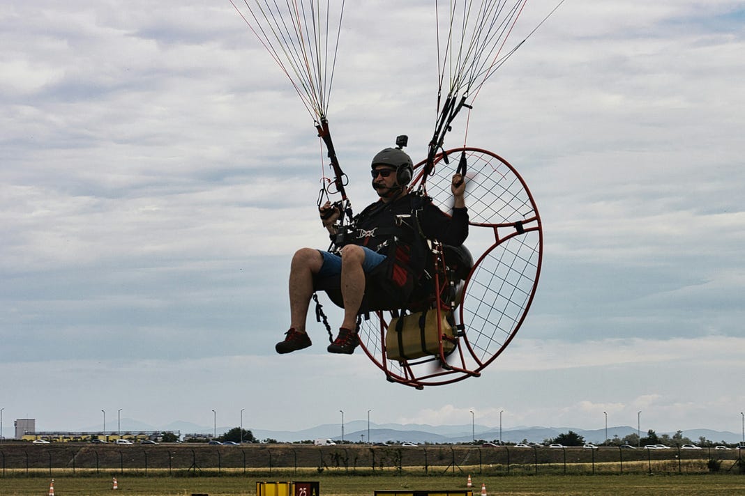 A man in a chair, flying with what is assumed are balloons attached to the chair.