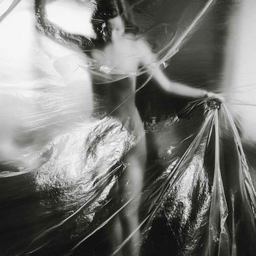 a black and white photo of a woman wrapped in plastic