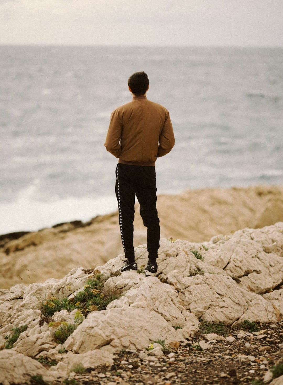a man standing on top of a rocky beach next to the ocean