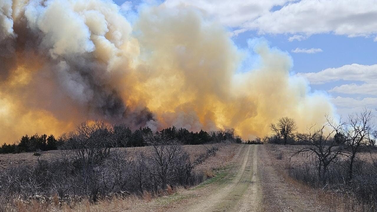 Smoke and fire blaze above a tree line in Kansas.