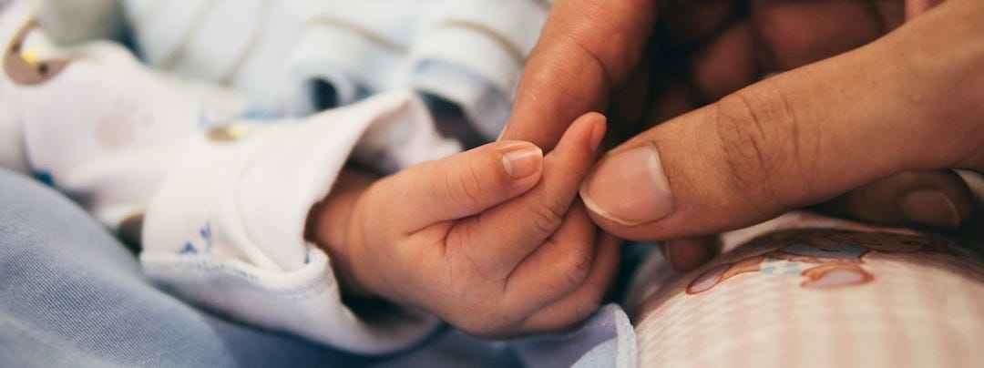 person holding baby's index finger