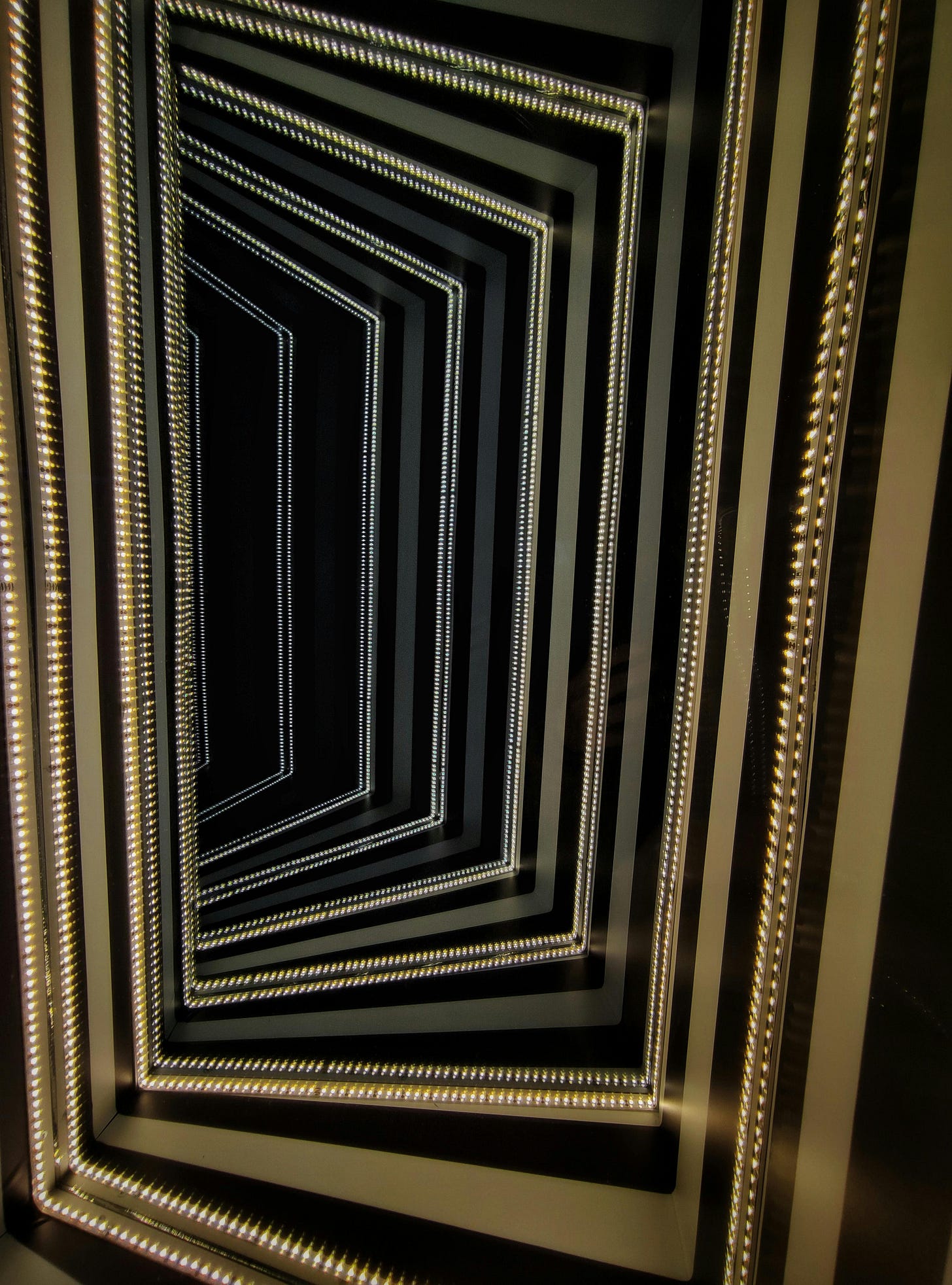 A golden mirror creates a dark, receding, infinite hallway.