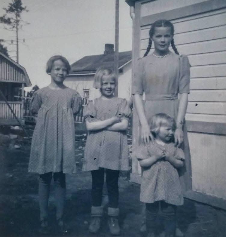 Black and white photo of four little girls in summer dresses.