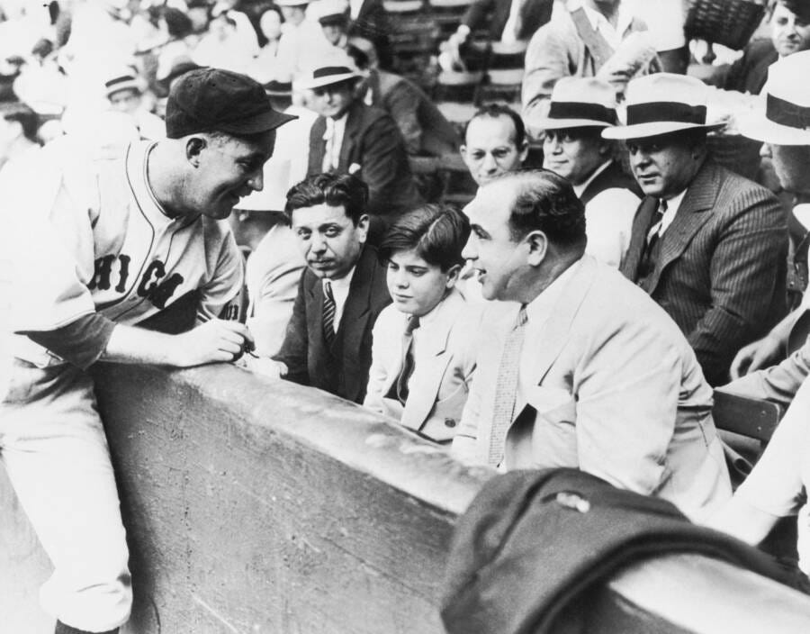 Gabby Hartnett signs a baseball for Al Capone and his son.