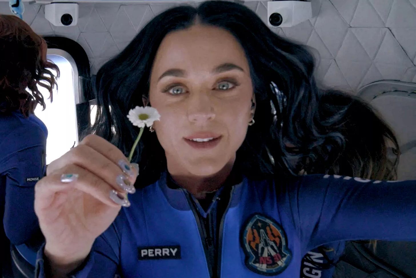 Katy Perry holds a daisy while floating in zero-gravity during their Blue Origin flight to space