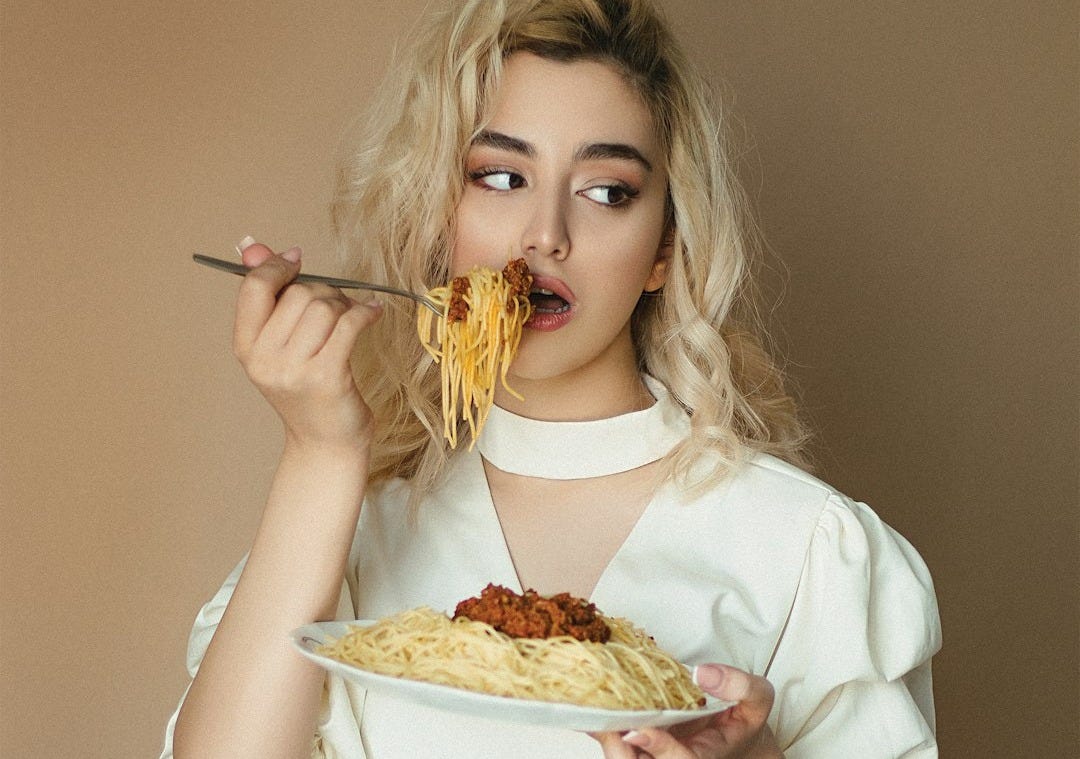 woman in white long sleeve shirt holding fork and eating pizza woman in white long sleeve shirt holding fork and eating pizza