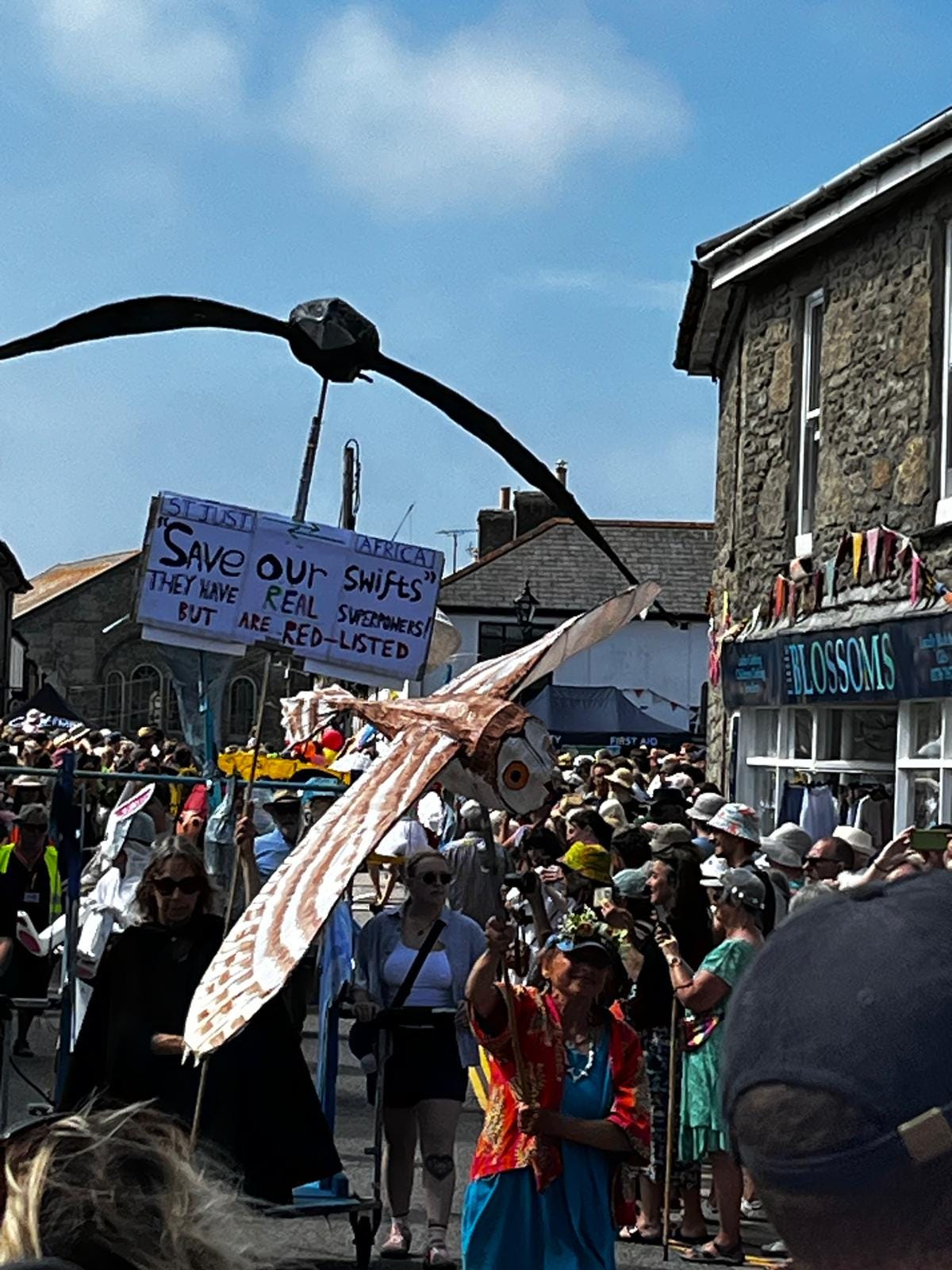 large paper birds fly along the street in a local summer festival