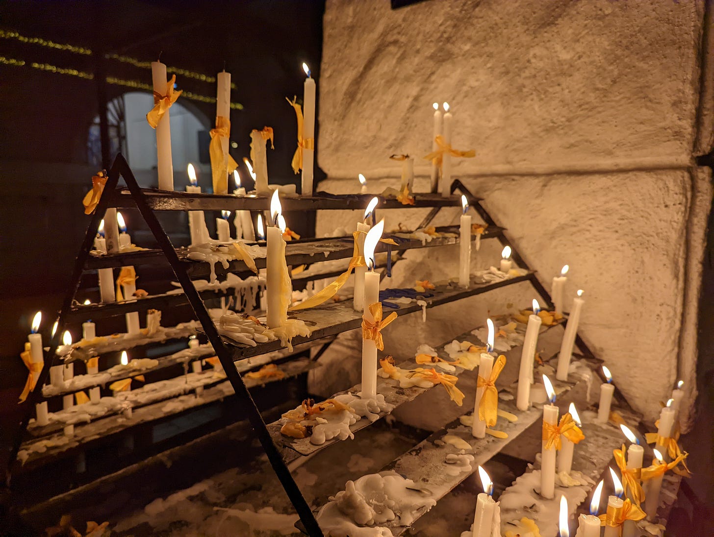 One of two candle stations inside Violago Quasi-Parish showing lit, unlit, and melted candles